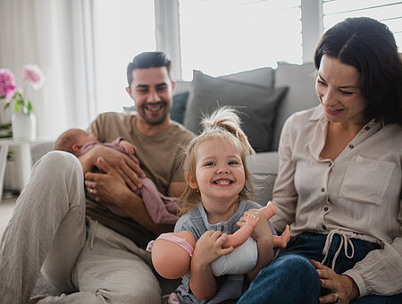 Happy young family with newborn baby and little girl enjoying time together at home.