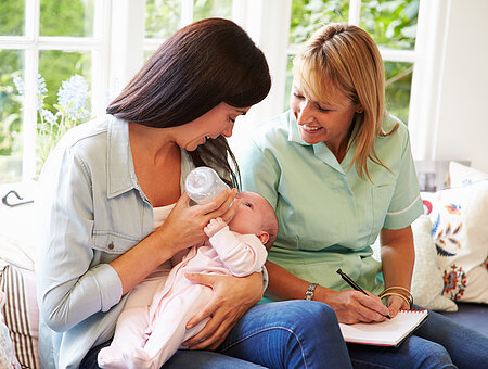 Mother With Baby Meeting With Health Visitor At Home